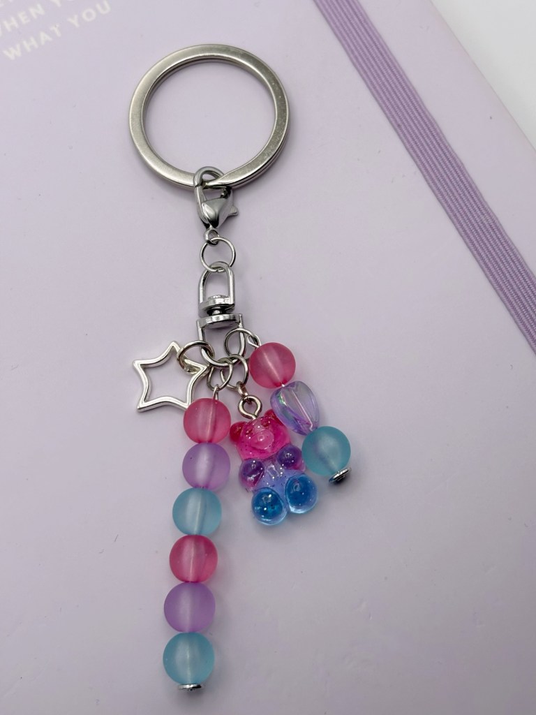 Photograph of a pink, purple, and blue charm on a keyring.